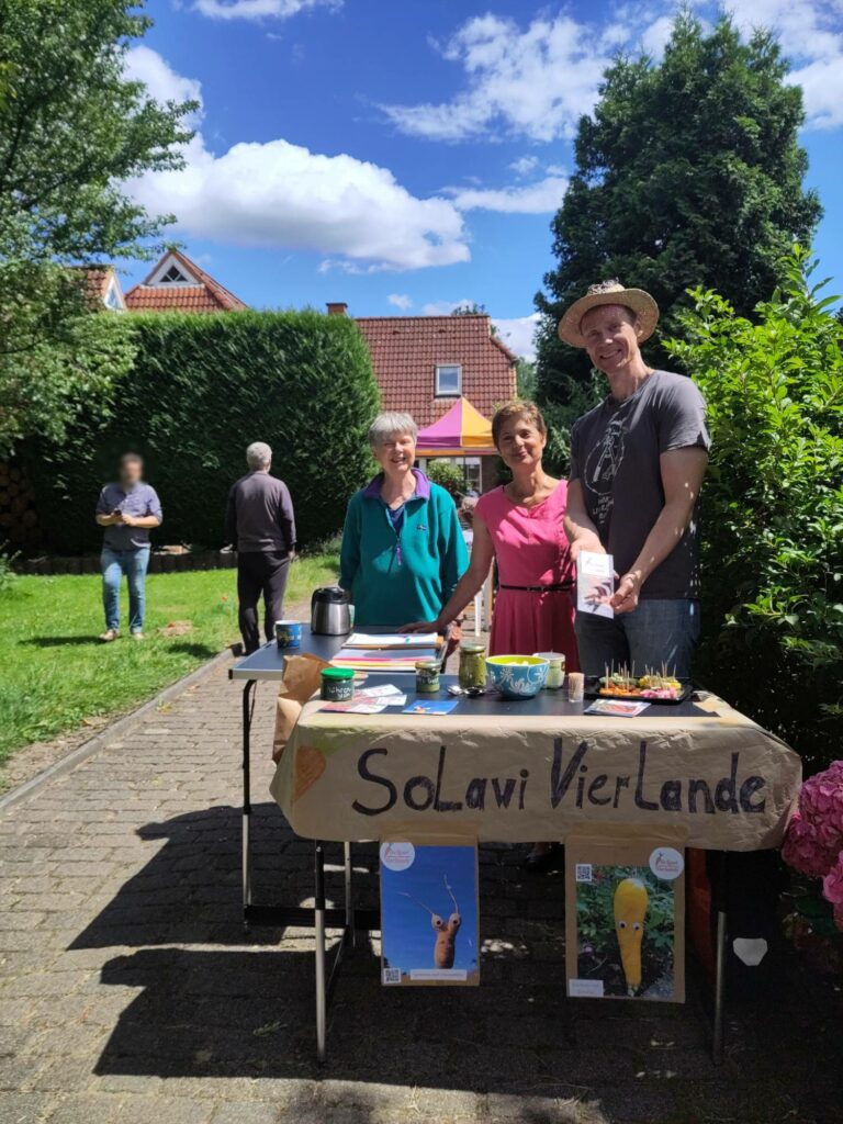 Die SoLawistas Dagmar, Christine und Carsten hinter dem SoLawi Infostand auf der Einfahrt von Christines Nachbarn.