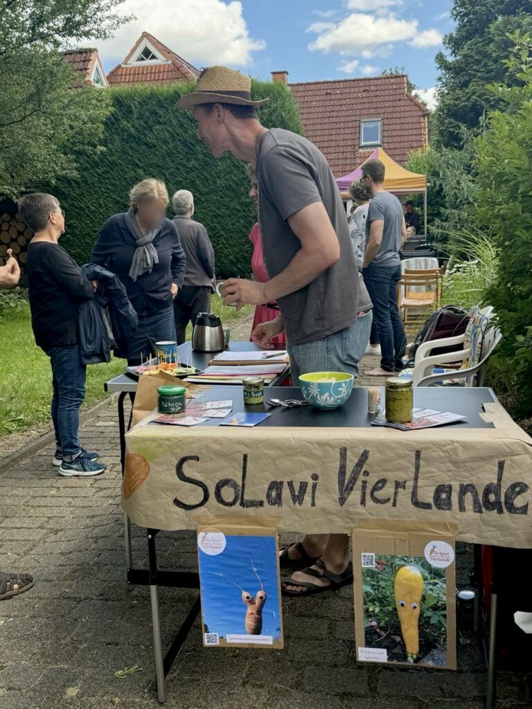 SoLawista Carsten erklärt am Infostand einer Person, wie die SoLawi funktioniert.